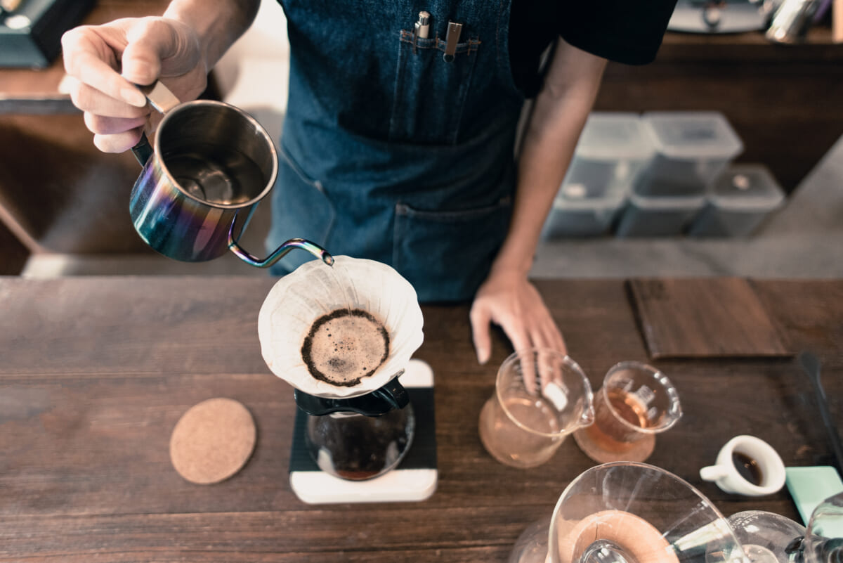 Hand drip coffee Barista with blue apron pouring hot water on roasted coffee ground with filter | コーヒーステーション