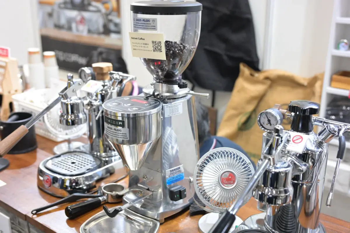 コーヒー豆が満たされたグラインダーを中心に、複数のエスプレッソマシンや関連器具が並ぶ専門的なコーヒーカウンター