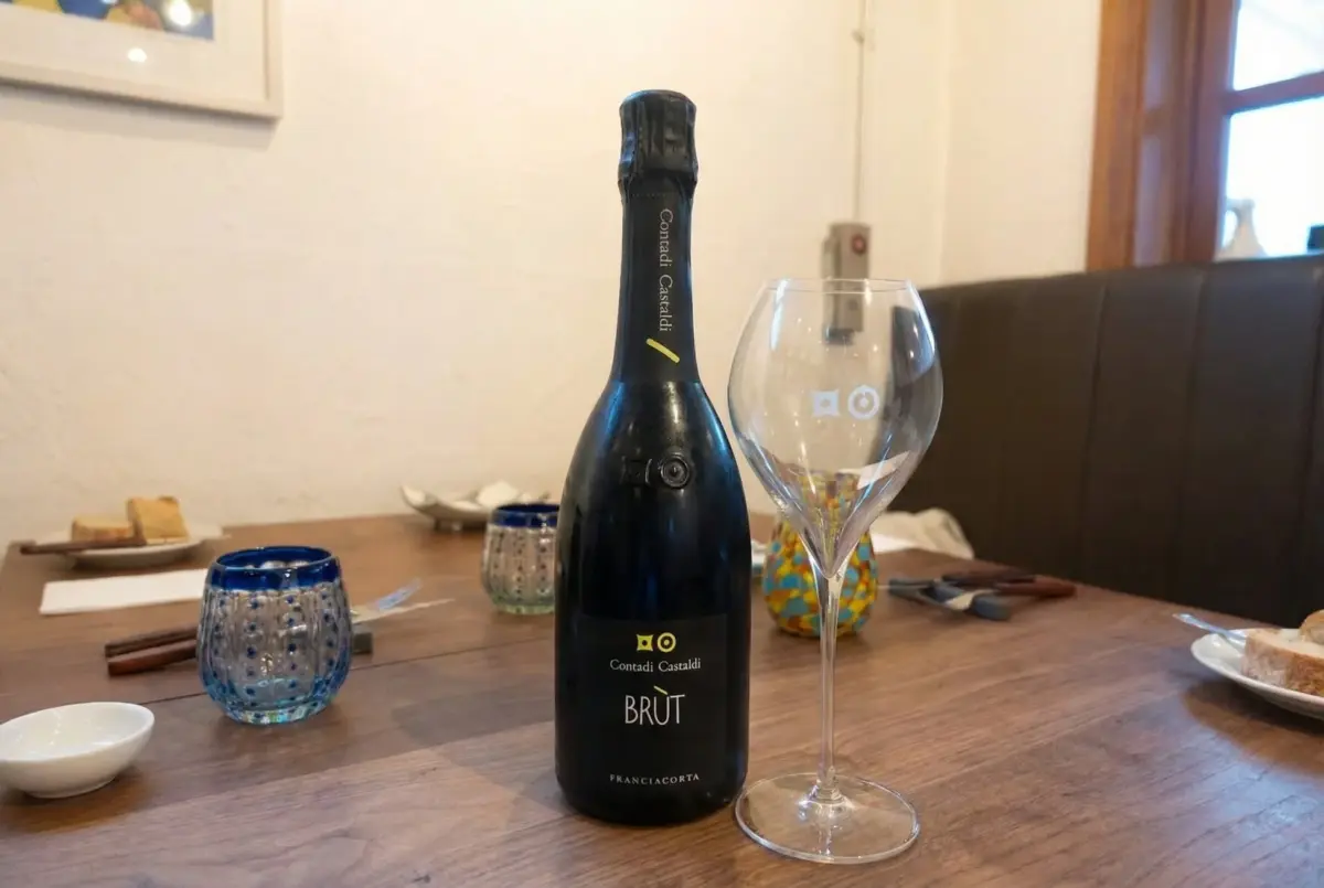 木製のテーブルに置かれたスパークリングワインのボトルと空のワイングラス