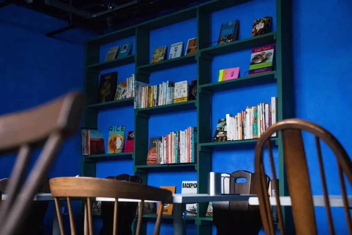 HAVE MORE CURRYの鮮やかな青い壁と緑色の本棚が特徴的な店内