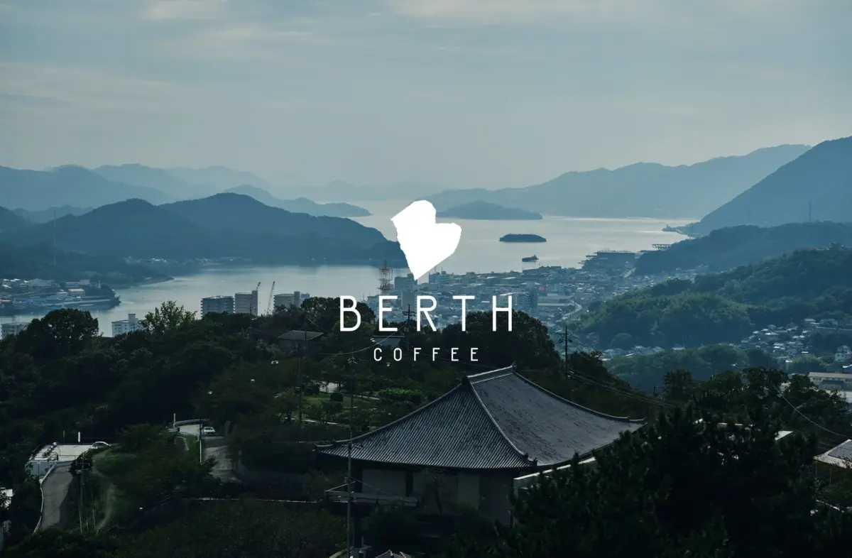 BERTH COFFEEロゴと穏やかな海と山々に囲まれた街並み