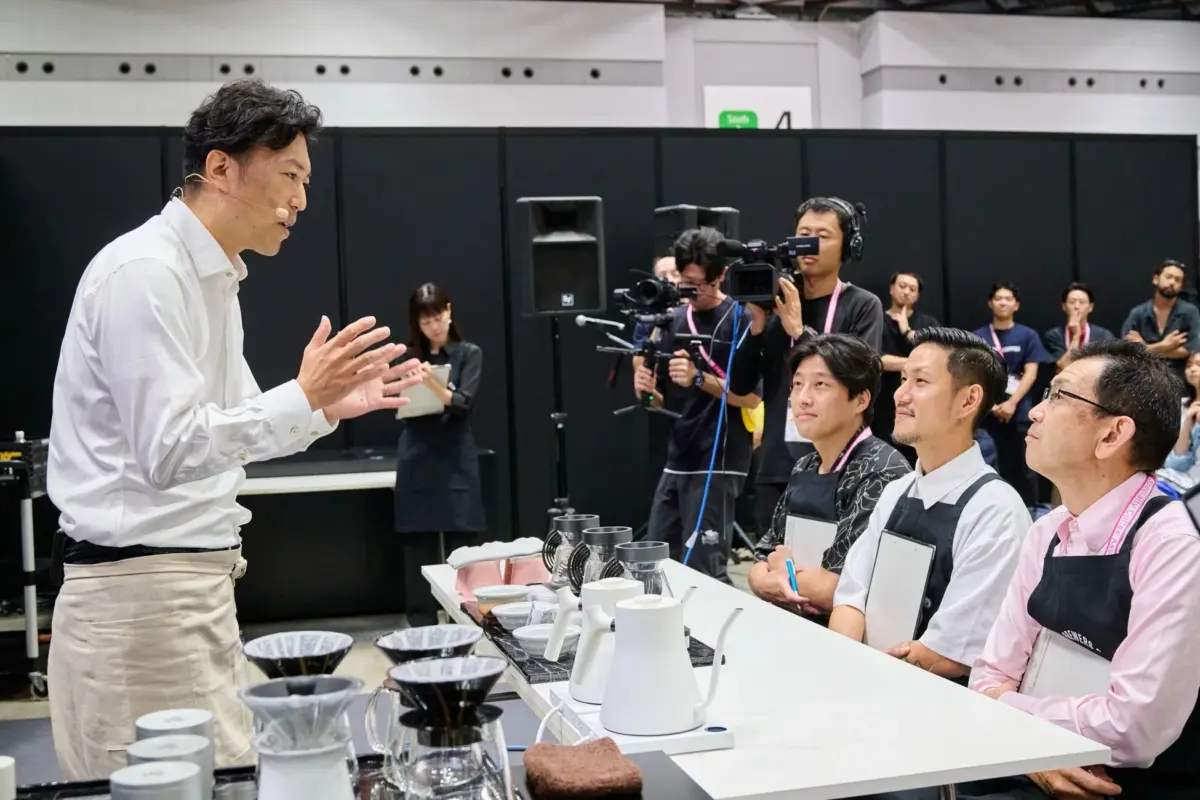 コーヒーイベントで、バリスタが聴衆に向けてドリップコーヒーのデモンストレーションを行っている様子