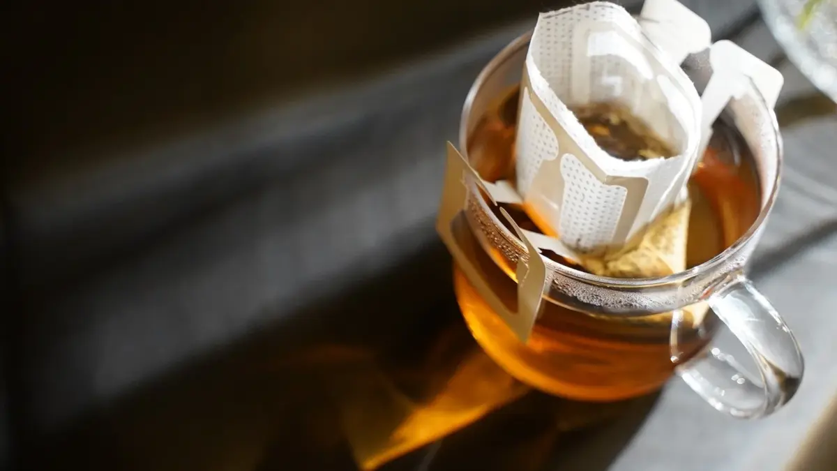 透明なマグカップにドリップ式のコーヒーフィルターがセットされ、飲み物を淹れる準備をしている様子を捉えた画像です。温かい飲み物の準備風景が、落ち着いた雰囲気で表現されています。