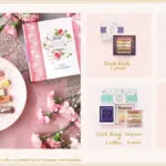 Pink themed Mothers Day gift layout with a Mille mercis box lace tablecloth and pink flowers surrounding ceramic plate with assorted stick rusk pastries