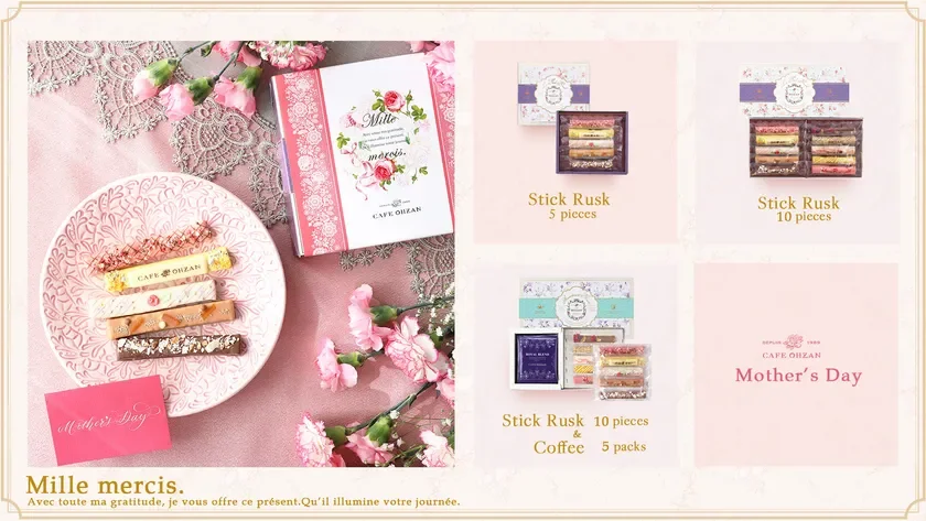 Pink themed Mothers Day gift layout with a Mille mercis box lace tablecloth and pink flowers surrounding ceramic plate with assorted stick rusk pastries