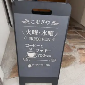 Outdoor chalkboard sign in Japanese advertising coffee and cookies for 700 yen takeout OK mentions TueWed limited open