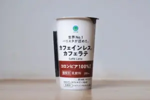 Tall white Japanese café latte bottle with a red middle band and Japanese text on a light wooden surface