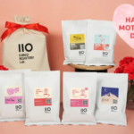 White IIO IlMIO Roastery Lab coffee bags arranged on a pink backdrop with red carnations and a pink heart reading Happy Mothers Day