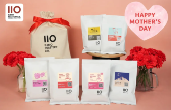 White IIO IlMIO Roastery Lab coffee bags arranged on a pink backdrop with red carnations and a pink heart reading Happy Mothers Day