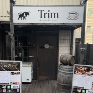 4d287fa0310d53ccebef87011c592e79 | コーヒーステーション Exterior of a cafe named Trim with a black dog and coffee cup logo on the sign