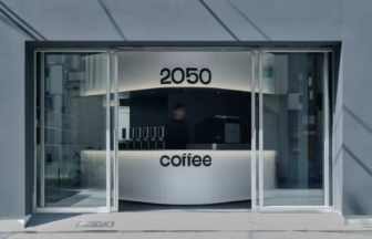 Futuristic coffee shop counter visible through glass doors with 2050 above and coffee on the front panel