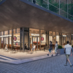 Modern cafe storefront with glass walls outdoor seating and pedestrians along a paved sidewalk under a large overhang