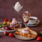 Assortment of Häagen Dazs desserts on a table ice cream scoops on pastries a croissant with ice cream strawberries a tall whipped cream dessert and coffee edges visible