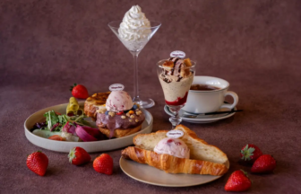 Assortment of Häagen Dazs desserts on a table ice cream scoops on pastries a croissant with ice cream strawberries a tall whipped cream dessert and coffee edges visible