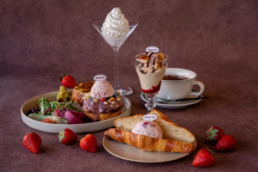 Assortment of Häagen Dazs desserts on a table ice cream scoops on pastries a croissant with ice cream strawberries a tall whipped cream dessert and coffee edges visible