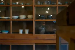 Wooden display cabinet with white bowls and blue ceramic dishes arranged on shelves