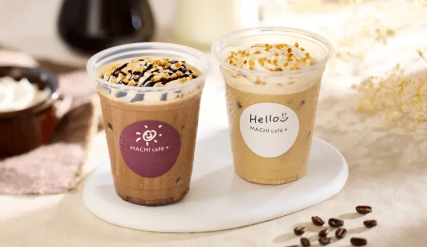 Two iced coffee drinks with whipped cream on a white plate left with chocolate drizzle right with nuts and a cream topping