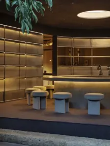 8b40e797238f4dc94c1dcde8829d2f6c | コーヒーステーション Circular bar with warm backlighting gray upholstered stools and metallic shelves in a modern lounge