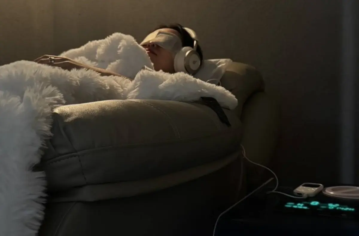 暗い部屋でアイマスクとヘッドホンを着用してリラックスする人物
