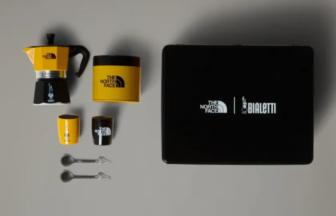 Collaboration coffee set: yellow and black Moka pot, two small cups, spoons, and a black box with The North Face and Bialetti logos on a gray background.