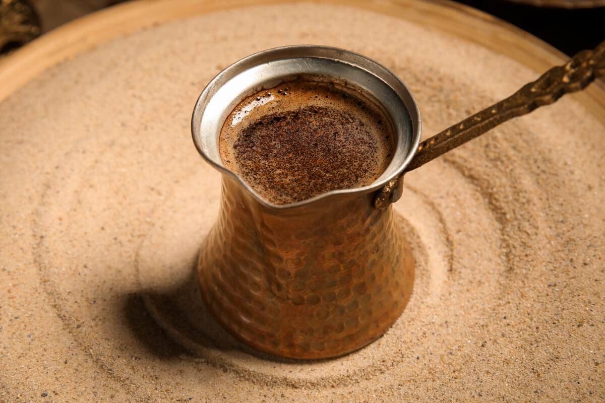 Copper cezve Turkish coffee pot in a bed of hot sand ready for brewing
