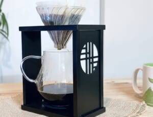 Black coffee dripper stand with glass carafe and metal pour over cone ready for brewing on a wooden table