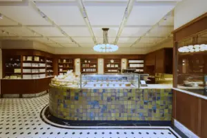 Curved pastry display counter with mosaic tiles showcasing baked goods in a warm wood accented bakery interior