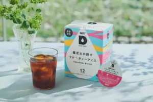 Colorful drip pod box with Seasonal Blend label beside a glass of iced coffee on a light table outside