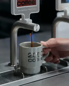 b8aedbd8469f6382d45196704b83b86c | コーヒーステーション Espresso machine pouring coffee into a gray mug labeled 2050 coffee held by a hand