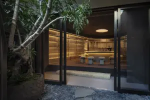 baa42353b18acb49608454920c355e67 | コーヒーステーション Open glass doors reveal a warm modern bar with a circular counter and padded stools inside