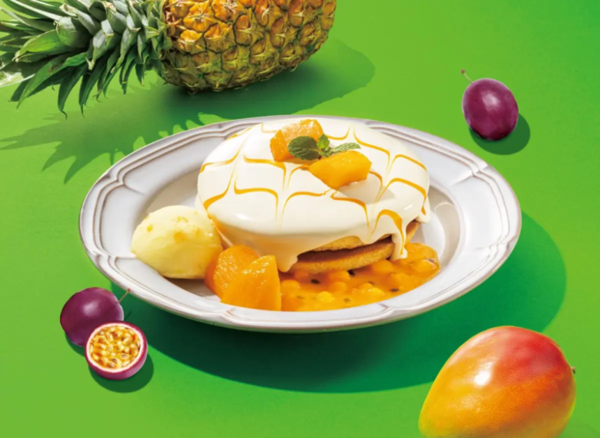 Dessert plate featuring a frosted cake with mango pieces mint and caramel drizzle on a white plate against a bright green background with tropical fruits nearby