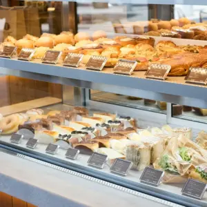 Display case filled with assorted baked goods croissants pastries cakes and sandwiches in a bakery