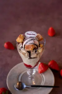 Häagen Dazs sundae in a glass with vanilla ice cream chocolate drizzle and pastry chunks topped with a Häagen Dazs label