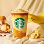 Starbucks iced beverage with layered yellow and brown tones logo visible set on a beige fabric with bananas and dessert items nearby