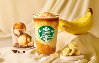 Starbucks iced beverage with layered yellow and brown tones, logo visible, set on a beige fabric with bananas and dessert items nearby