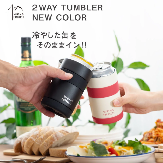 Two hands clink black and white WENS Products 2 way tumblers over a table with bread and salad