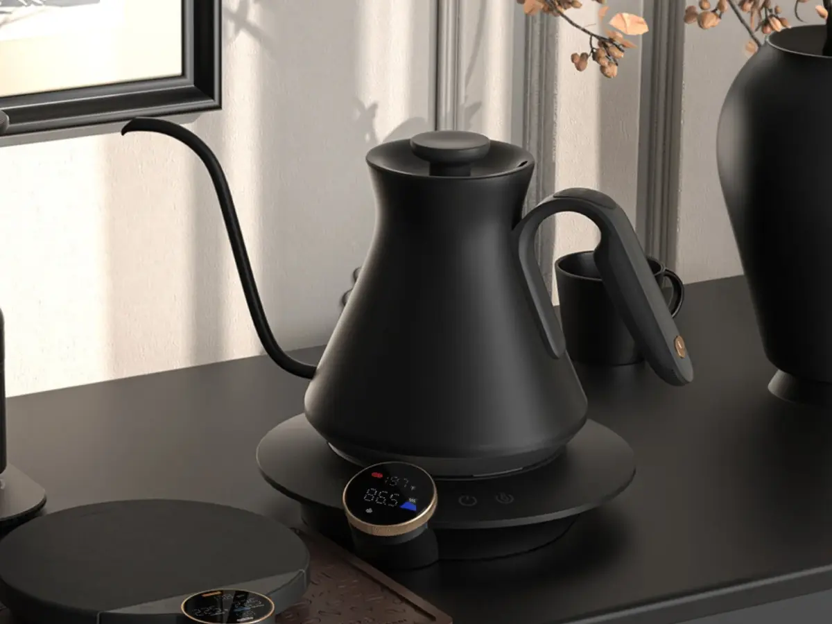 モダンな黒い電気ドリップケトルとデジタルスケールが写っています。ケトルにはデジタル温度表示があり、精密なコーヒー抽出を可能にします。スタイリッシュで機能的なコーヒー器具が整然と配置された、洗練されたコーヒーブレイクの風景です。