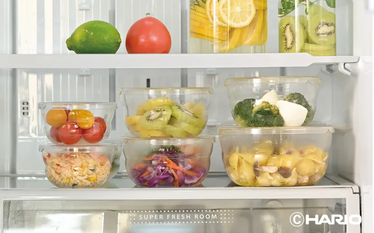 Assorted prepped fruits and vegetables in clear bowls on a refrigerator shelf ready for meals