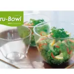 Glass bowls on a wooden tray with a fresh salad in the right bowl green Kar Bowl logo in the top left corner