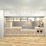 Modern cafe counter inside a light open storefront with menu boards above and a wood toned front featuring TORIMARU x TANITA CAFE design