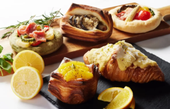 Assorted pastries on a wooden board with lemon slices and citrus topped croissants featuring savory and sweet fillings