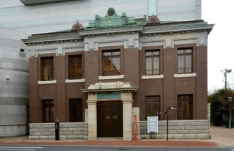 Two story brick historic building with a stone entryway and double wooden doors on a city street