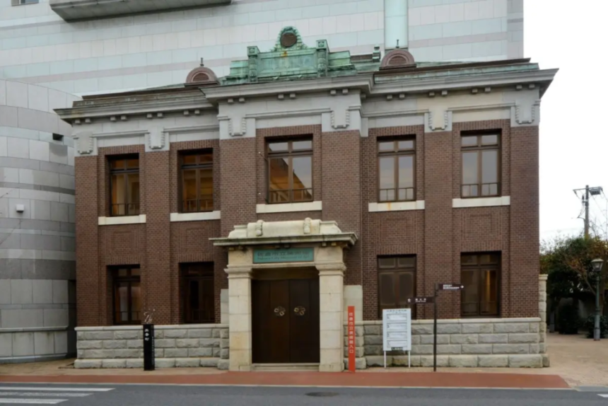 Two story brick historic building with a stone entryway and double wooden doors on a city street