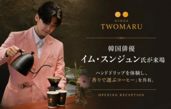 Person in a pink suit pours coffee from a black gooseneck kettle at a promotional backdrop for Ginza TWOMARU, with Japanese text and 'Opening Reception' at the bottom.