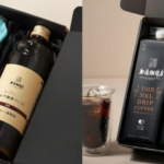 Gift box with a dark bottle labeled coffee and a wrapped bouquet with a Thank You tag inside a black box on the left and a row of The Nel Drip Coffee cartons with a glass of iced coffee on the right