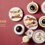 Overhead view of assorted pastries and cups of black coffee arranged on a burgundy table with ROYAL BLEND branding on the left French tagline shown