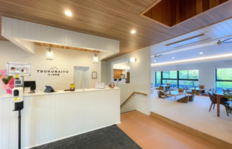Reception desk in a bright airy lobby with a wood ceiling and a seating area visible beyond the counter