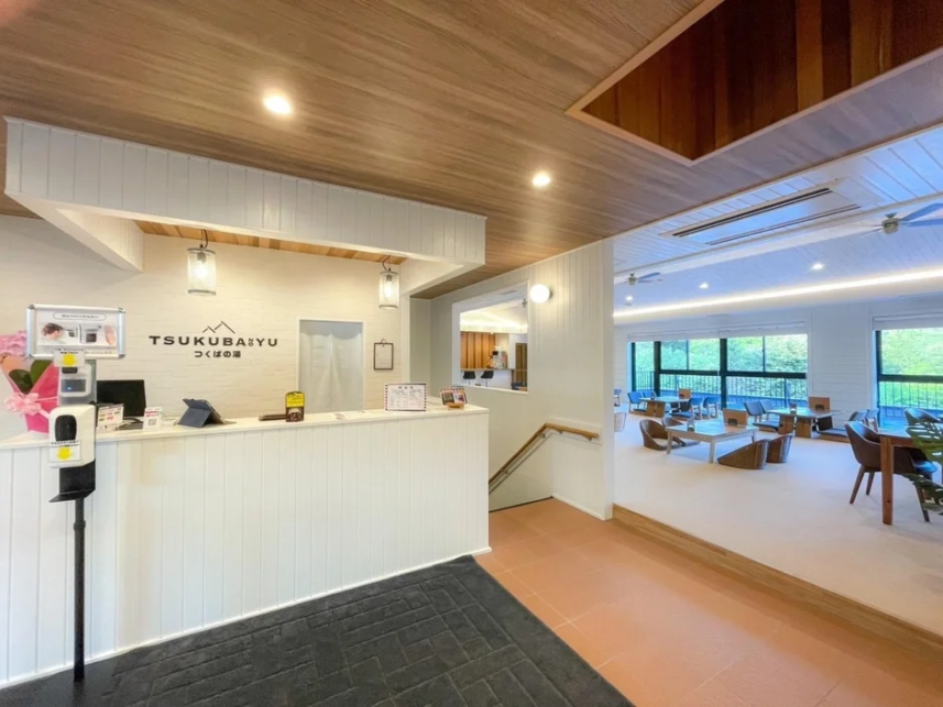 Reception desk in a bright airy lobby with a wood ceiling and a seating area visible beyond the counter