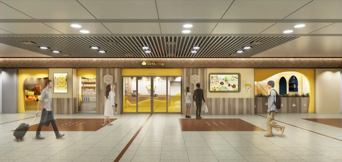 黄色を基調とした「ぴよりん village」というカフェ＆ギフトショップの店舗外観です。明るい商業施設や駅の通路に面しており、可愛らしいひよこのキャラクターグッズやディスプレイが並んでいます。数人の通行人が見られます。