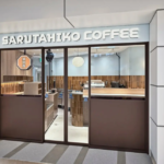 Sarutahiko Coffee storefront with glass doors and brown panels warm wooden interior visible inside